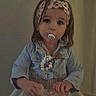 Fybie a rejoint le concours — aidez-le/la à gagner de superbes lots ! toddler, child, pacifier, headband, indoor, bottle, clothing, curly_hair, portrait, standing, floor, wall, jacket, beads, person, cute, young_child, casual, light, baby