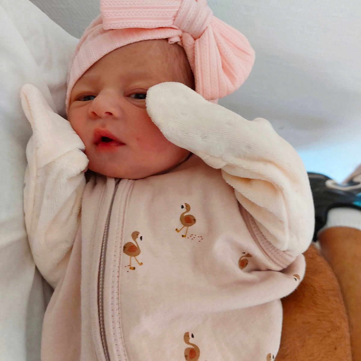 Cassie participe au concours pour gagner de l'argent avec cette photo : baby, bow, clothing, cozy, cute, face, flamingo_pattern, hand, headband, infant, lying_down, mittens, newborn, person, pink, portrait, resting, skin, sleepwear, soft