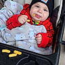 baby, child, infant, stroller, beanie, red_outfit, blanket, snack, puffs, tongue_out, smiling, portrait, cozy, outdoor, seated, carriage, baby_clothing, playful, face, photography