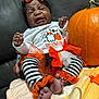 baby, child, crying, halloween, pumpkin, costume, tutu, headband, striped_leggings, orange, black, white, couch, blanket, indoor, holiday, festive, infant, cute, portrait
