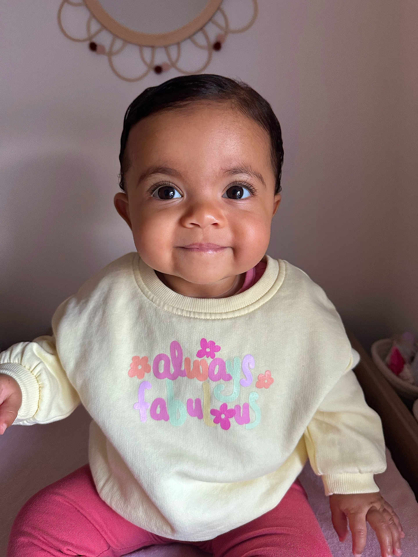 Jennah participe au concours pour gagner de l'argent avec cette photo : baby, child, smile, face, sweater, pink_pants, indoor, portrait, cute, eyes, hands, seated, cozy_clothing, mirror, decor, skin, person, infant, young_child, happy