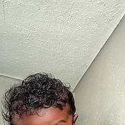 Kario is registered to the contest to win money with this photo: child, toddler, curly_hair, big_eyes, face, skin, person, indoor, ceiling, wall, clothing, long_sleeve, expression, cute, portrait, baby, young_child, resting, looking, soft_surface