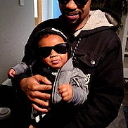 Kario joined the competition — help win amazing prizes! adult, baby, beard, black_clothing, casual, child, cool, face, family, hand, hat, holding, hood, hoodie, indoor, jacket, person, smile, sunglasses, toddler