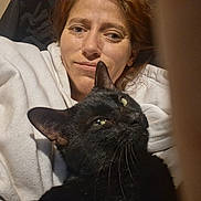 Sugar Dude is registered to the contest to win money with this photo: woman, cat, black_cat, indoors, selfie, face, pet, cozy, hoodie, expression, close_up, green_eyes, feline, domestic_animal, relaxing, cute, portrait, snuggling, casual, comfort