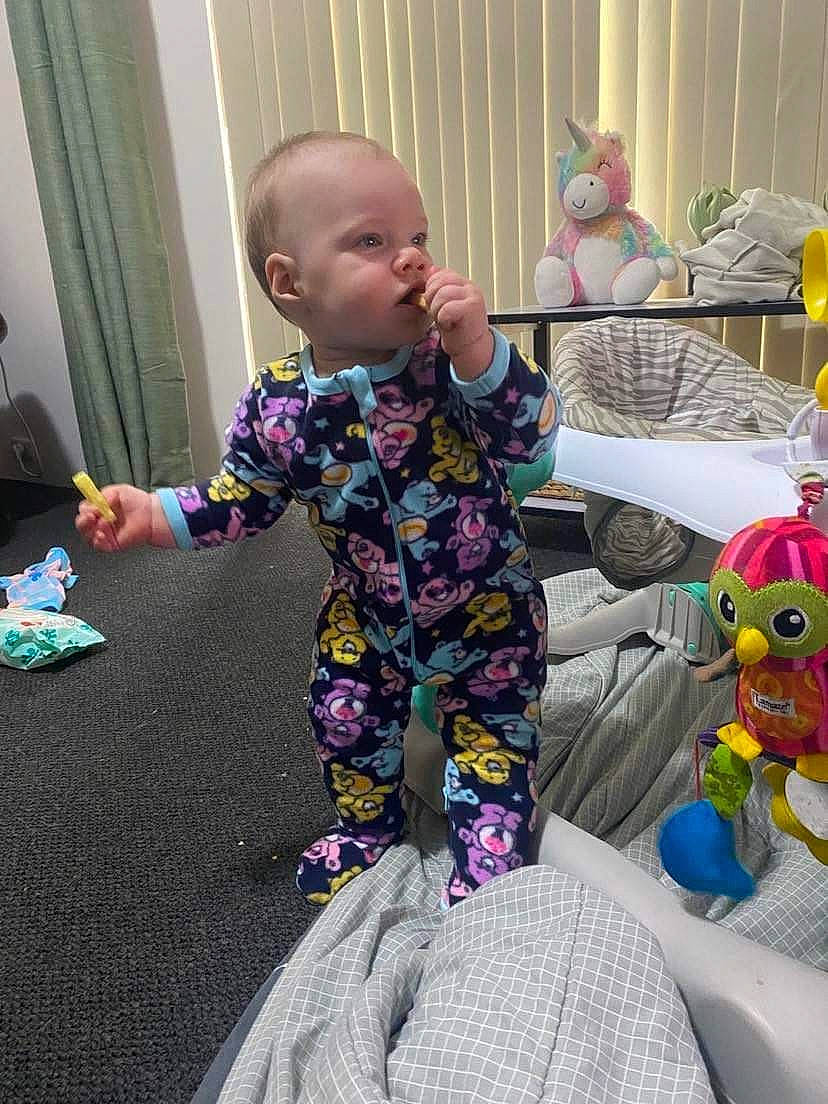 Lailani is registered to the contest to win money with this photo: baby, baby_toddler_clothing, baby_toys, child, flooring, fun, happy, lap, pajamas, person, play, purple, room, sitting, sleeve, smile, sock, stuffed_toy, t_shirt, toddler