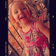 Ruthie Kay is registered to the contest to win money with this photo: background, casual, child, curly_hair, daylight, dress, floral_dress, furniture, happy, kodak_portra_400, outdoor, person, pink, plant_pot, porch, railing, rug, smiling, toddler, vintage_frame