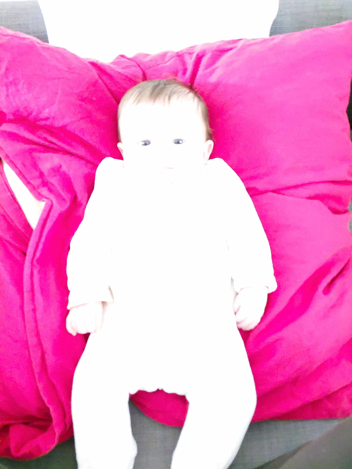 Lilou participe au concours pour gagner de l'argent avec cette photo : baby, infant, child, pillow, bedding, overexposed, white_clothing, magenta_pillow, pink, couch, sofa, indoor, lying_down, portrait, head, face, hands, soft_texture, brightness, cozy