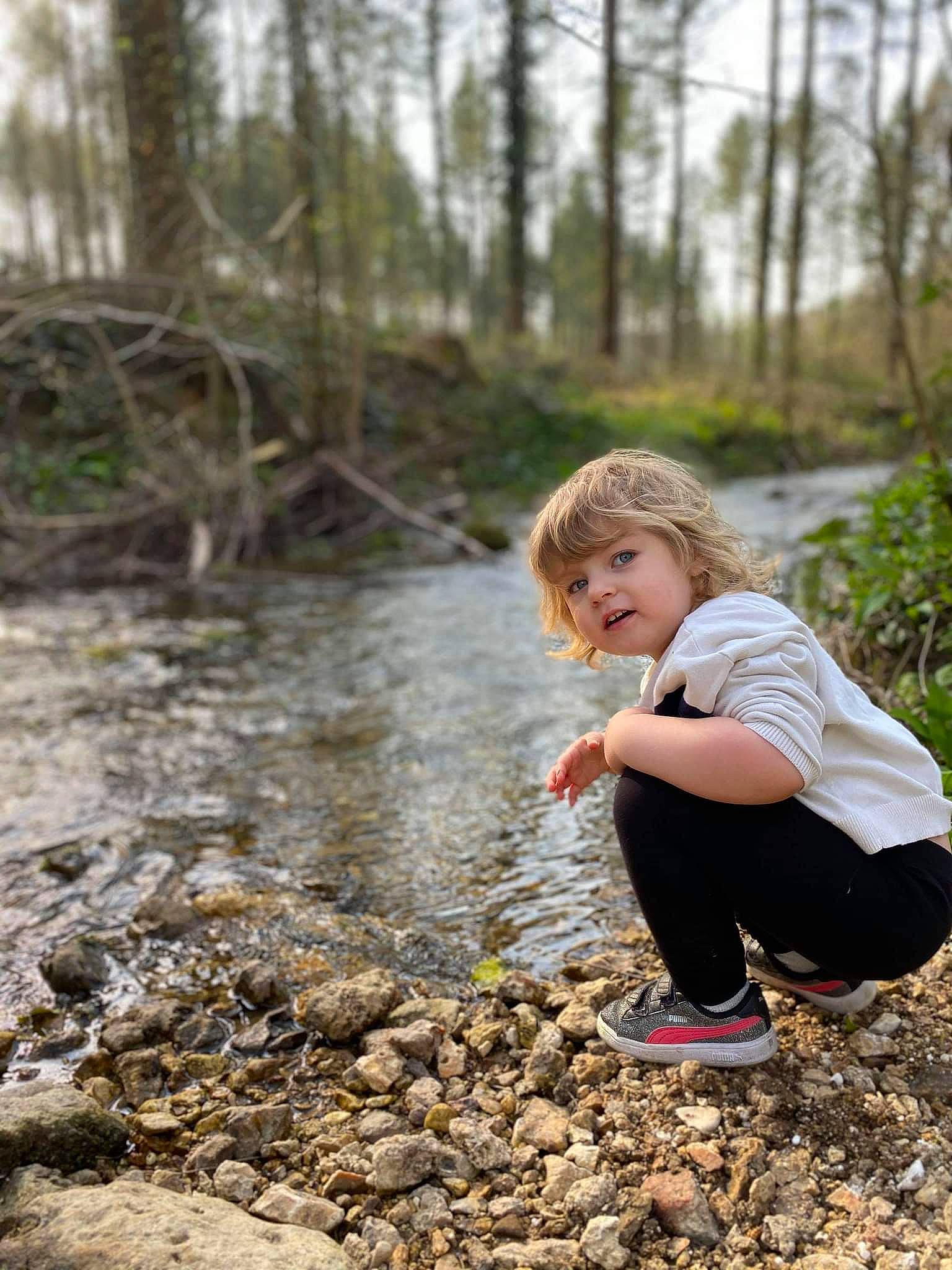 Lola participe au concours pour gagner de l'argent avec cette photo : bank, forest, fun, grass, happy, landscape, leisure, natural_landscape, people_in_nature, person, plant, recreation, rock, sitting, soil, stream, toddler, trail, tree, wood