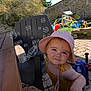Alba a rejoint le concours — aidez-le/la à gagner de superbes lots ! toddler, child, hat, bubble, outdoor, playground, toy, yellow_clothing, pink_hat, face, smile, sunlight, plastic_chair, garden, table, stone_wall, play_equipment, daytime, person, curious