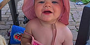 Alba a rejoint le concours — aidez-le/la à gagner de superbes lots ! toddler, child, pink_hat, pink_clothing, blanket, dog, outdoor, patio, stone_floor, smiling, drool, sunhat, footwear, toy, garden, greenery, chair, table, happy, person