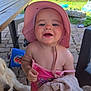 toddler, child, pink_hat, pink_clothing, blanket, dog, outdoor, patio, stone_floor, smiling, drool, sunhat, footwear, toy, garden, greenery, chair, table, happy, person