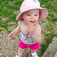 Alba participe au concours pour gagner de l'argent avec cette photo : toddler, child, outdoor, grass, pebbles, hat, pink_shorts, white_shoes, blue_eyes, playful, curious, summer_clothing, person, face, hand, footwear, nature, sunhat, casual, standing