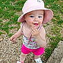 toddler, child, outdoor, grass, pebbles, hat, pink_shorts, white_shoes, blue_eyes, playful, curious, summer_clothing, person, face, hand, footwear, nature, sunhat, casual, standing