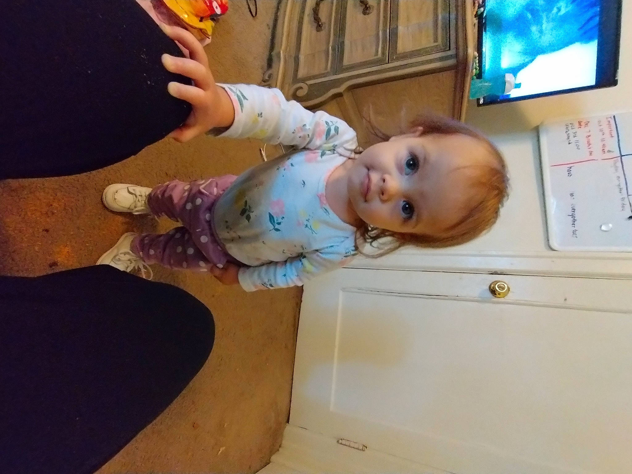 Sadie is registered to the contest to win money with this photo: arm, baby, baby_toddler_clothing, cable_television, cheek, child, finger, floor, flooring, fun, hand, hardwood, home_appliance, person, room, skin, smile, television, television_set, toddler