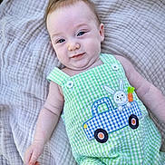 Gabriel is registered to the contest to win money with this photo: baby, infant, child, blanket, green_clothing, romper, bunny_patch, blue_truck, smiling, cute, portrait, closeup, outdoor, soft_texture, fabric, happy, person, skin, head, hand