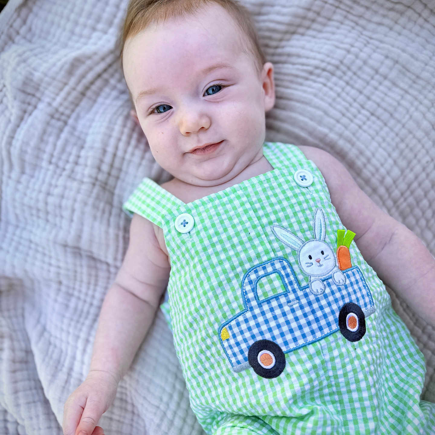 Gabriel is registered to the contest to win money with this photo: baby, infant, child, blanket, green_clothing, romper, bunny_patch, blue_truck, smiling, cute, portrait, closeup, outdoor, soft_texture, fabric, happy, person, skin, head, hand