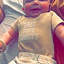baby, infant, smiling, clothing, dinosaur_pattern, bed, blanket, cute, child, happy, toddler, person, fabric, soft, lying_down, beige_shirt, pajamas, indoor, portrait, baby_girl