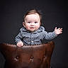 baby, child, smiling, waving, leather_chair, portrait, studio, cute, happy, black_background, button_up_shirt, plaid, young_child, face, head, person, furniture, sitting, expression, small_hand