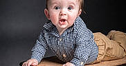 Ryder is registered to the contest to win money with this photo: baby, child, vintage_suitcase, blue_shirt, tan_pants, curious_expression, studio_lighting, portrait, indoor, infant, hands, face, eyes, mouth_open, clothing, cute, young, person, background, posing