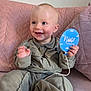 Oakley is registered to the contest to win money with this photo: baby, balloon, blue, child, couch, cozy, eyes, face, hand, happy, indoor, infant, knitwear, mouth, nose, pink, portrait, sign, sitting, smile
