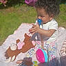 toddler, child, pacifier, curly_hair, toy, plush_toy, blanket, outdoor, sunlight, grass, colorful, playing, sitting, happy, baby_clothes, patterned_pants, soft_texture, nature, infant, cute