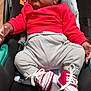 baby, sleeping, car_seat, red_sweater, gray_pants, sneakers, child, infant, footwear, clothing, seatbelt, indoors, cute, toddler, face, head, hand, resting, cozy, transportation