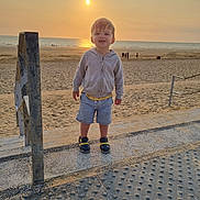 Sacha participe au concours pour gagner de l'argent avec cette photo : toddler, child, beach, sunset, sand, sea, ocean, clothing, hoodie, shorts, sandals, concrete, railing, outdoor, sky, sun, people, shadows, summer, vacation