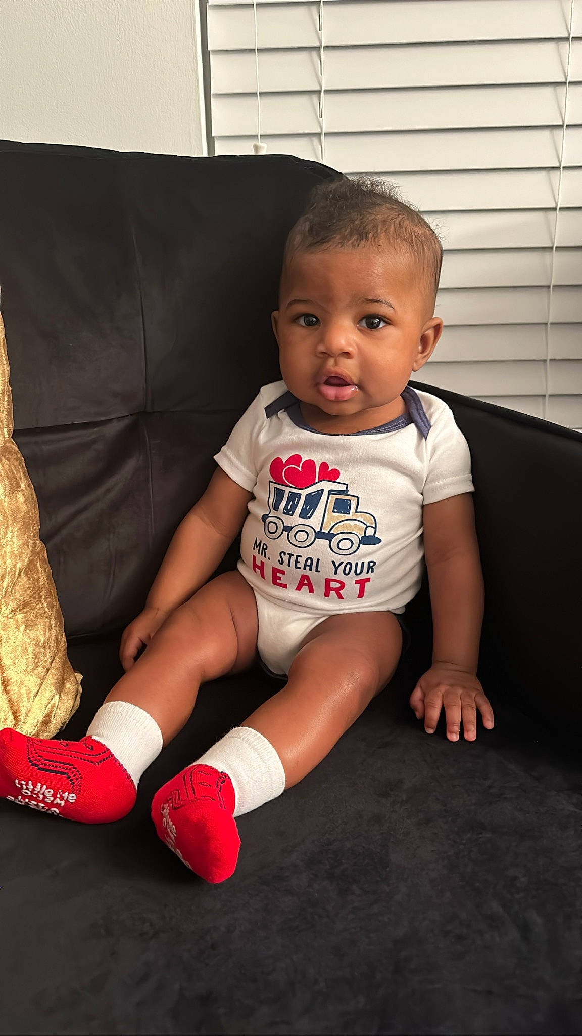Marcus Jr. is registered to the contest to win money with this photo: baby, baby_toddler_clothing, carmine, child, comfort, couch, finger, flooring, foot, human_leg, knee, lap, leg, pattern, person, sitting, skin, sleeve, sock, thigh