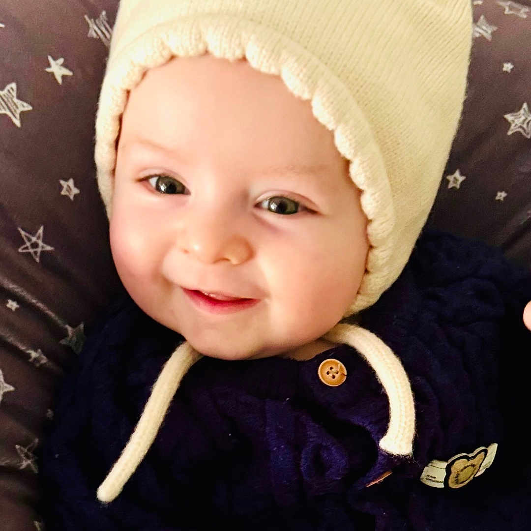 Omer a rejoint le concours — aidez-le/la à gagner de superbes lots ! baby, beanie, bonnet, cap, clothing, coat, couch, face, furniture, happy, hat, head, hood, jacket, newborn, pants, person, photography, portrait, smile