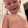child, toddler, smiling, wet_skin, bathroom, door, indoor, face, head, skin, expression, happy, teeth, short_hair, bare_chest, plumbing, light, wall, person, closeup