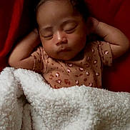 Hazel is registered to the contest to win money with this photo: baby, sleeping, blanket, red_background, cozy, infant, peaceful, soft_texture, child, cute, resting, warm, comfort, portrait, indoors, newborn, clothing, relaxed, face, hands_behind_head
