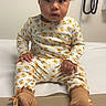 toddler, child, baby, sitting, medical_office, exam_table, floral_clothing, brown_socks, curly_hair, indoor, person, portrait, cute, young_child, waiting, healthcare, pediatric, expression, clothing, floor