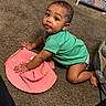 baby, child, crawling, green_shirt, pink_hat, carpet, indoor, furniture, curious, cute, earrings, skin, floor, diaper, person, one_child, toddler, play, home, young