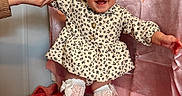 Alannah Carol joined the competition — help win amazing prizes! baby, child, smiling, happy, dress, socks, bow, hand, person, indoor, blanket, curtain, pigtails, cute, infant, playful, skin, face, standing, holding_hand