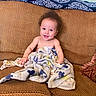 Kingstone joined the competition — help win amazing prizes! baby, child, smiling, blanket, couch, furniture, indoor, happy, person, portrait, seat, cozy, patterned_blanket, curly_hair, young_child, home, living_room, cute, infant, relaxed