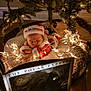 baby, christmas, holiday, santa_hat, sleeping, fairy_lights, blanket, book, polar_express, tree, decorations, festive, cozy, indoors, child, cute, warm_lighting, floor, relaxing, soft_texture
