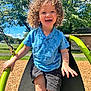 Holden is registered to the contest to win money with this photo: blue_shirt, child, curly_hair, cute, daylight, fun, greenery, happy, outdoor, park, person, playground, recreation, shorts, smiling, summer, sunny, swing, toddler, trees