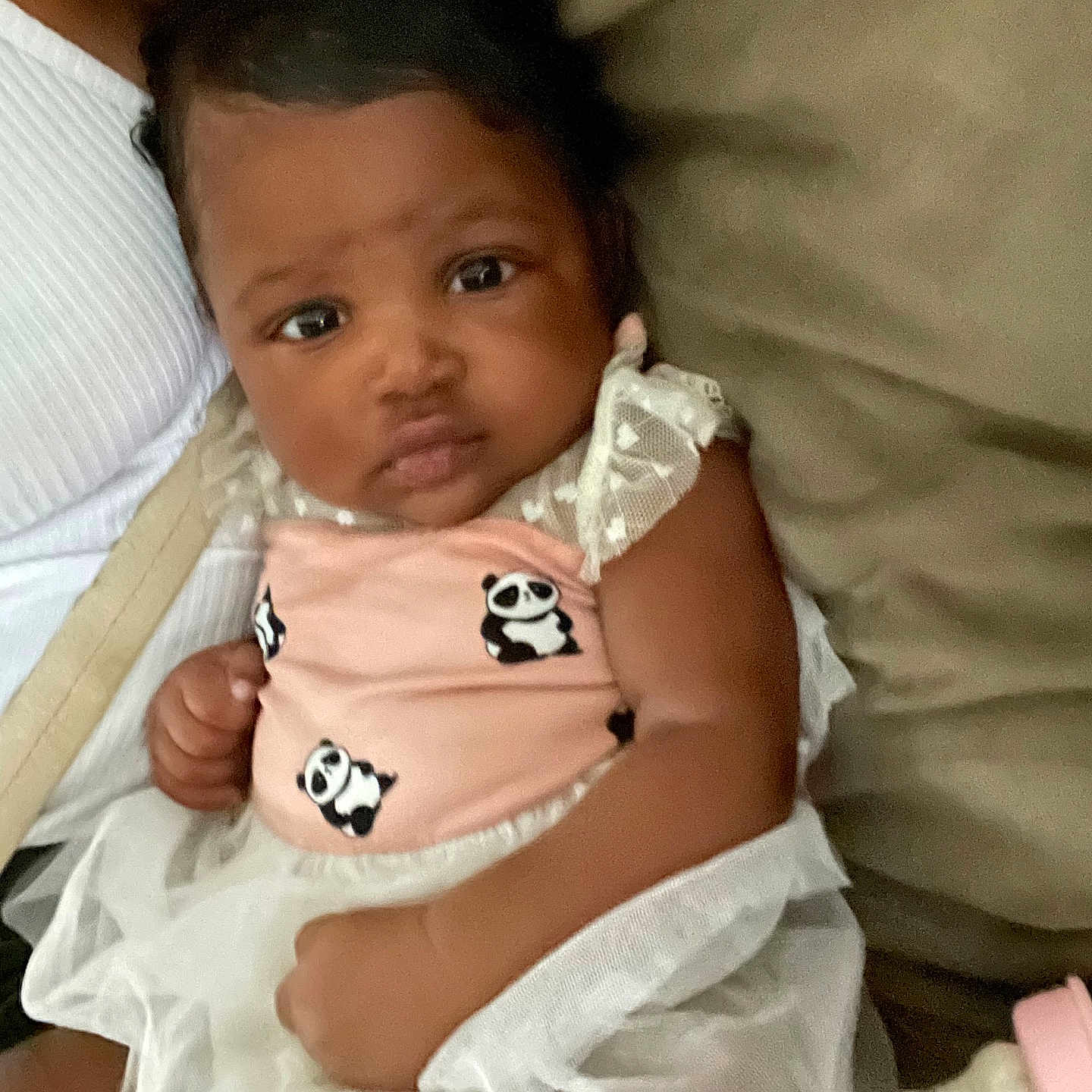 Liliana is registered to the contest to win money with this photo: baby, bottle, child, closeup, couch, curious, cute, dress, feeding, hand, head, indoors, infant, panda_print, person, pink_bow, portrait, skin, soft_background, white_tulle
