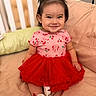 child, toddler, girl, smiling, portrait, red_dress, tutu, hair_bows, white_shoes, sitting, couch, pillows, indoor, home, baby, fashion, happy, face, cherry_pattern, photography