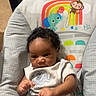 baby, child, infant, portrait, sitting, high_chair, curious, serious, face, eyes, hair, elephant, onesie, rainbow, cartoon, sun, palm_tree, indoor, furniture, photography