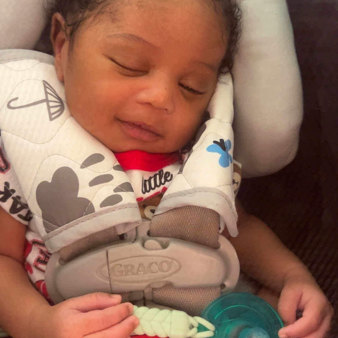 Dakylan is registered to the contest to win money with this photo: baby, infant, sleeping, curly_hair, portrait, car_seat, harness, pacifier, seated, indoors, close_up, face, hands, arms, blanket, clothing, safe, relaxed, child, photograph