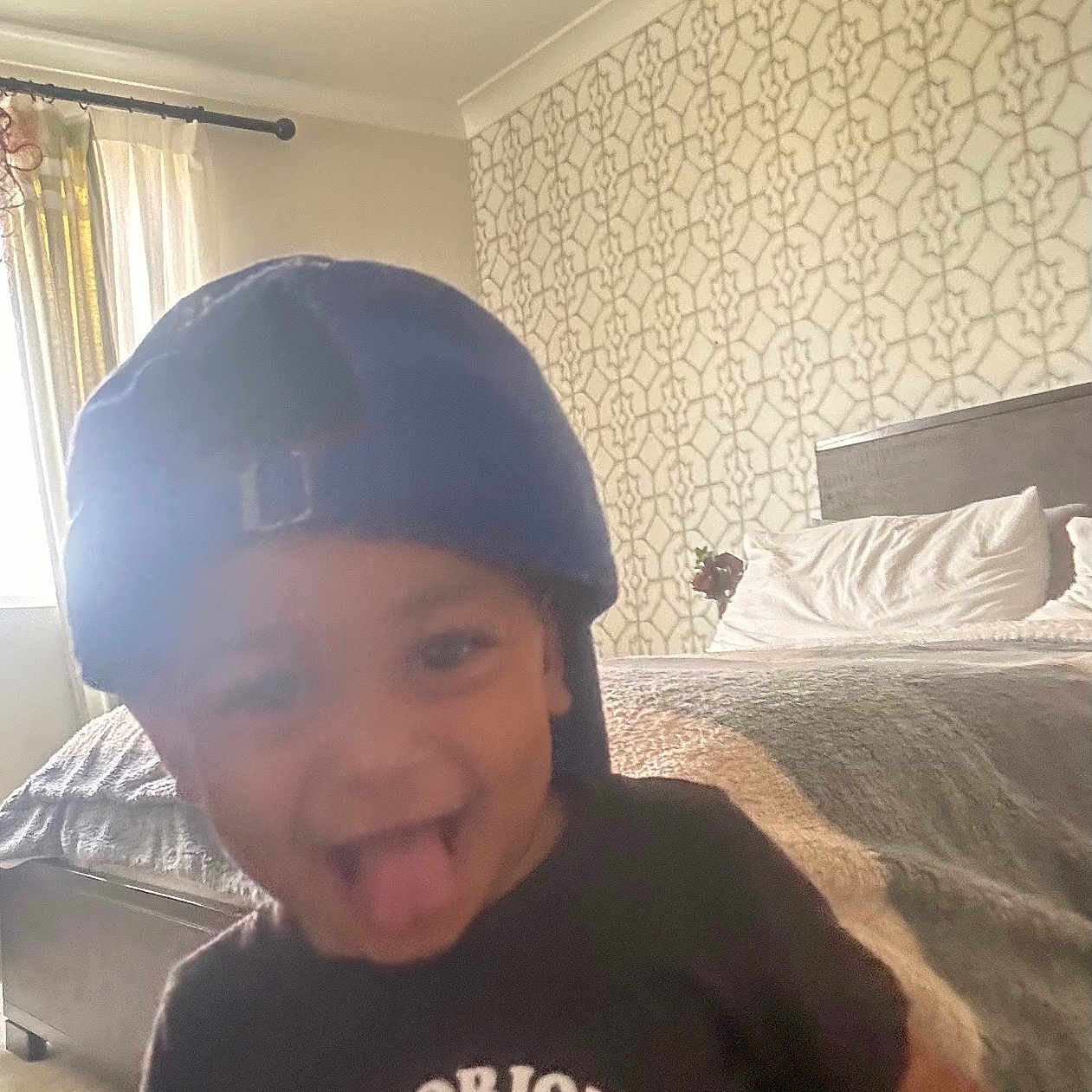 Jamir is registered to the contest to win money with this photo: baby, baseballcap, bed, bedroom, bodypart, cap, clothing, face, furniture, hat, head, helmet, indoors, interiordesign, mouth, person, photography, portrait, room, t_shirt