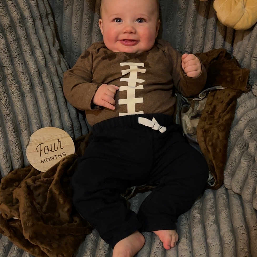 Cole joined the competition — help win amazing prizes! baby, baby_clothes, blanket, child, clothing, couch, cozy, cute, face, feet, footwear, happy, indoors, infant, person, plush_toy, portrait, sitting, smiling, soft_toy