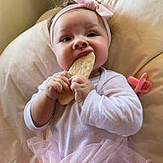 Chloe is registered to the contest to win money with this photo: baby, child, girl, headband, bow, tutu, pink, cracker, hands, cushion, pacifier, sitting, cute, clothing, infant, soft, indoor, portrait, face, chewing