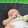 Ray is registered to the contest to win money with this photo: baby, sleeping, outdoor, grass, green, black, clothing, mickey_mouse, infant, cute, peaceful, hand, face, skin, toddler, resting, soft_light, nature, summer, relaxation