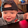 Ray joined the competition — help win amazing prizes! toddler, child, cap, smile, table, indoor, wood_paneling, face, shirt, happy, person, blur, black_cap, baby, furniture, tabletop, expression, joy, room, casual