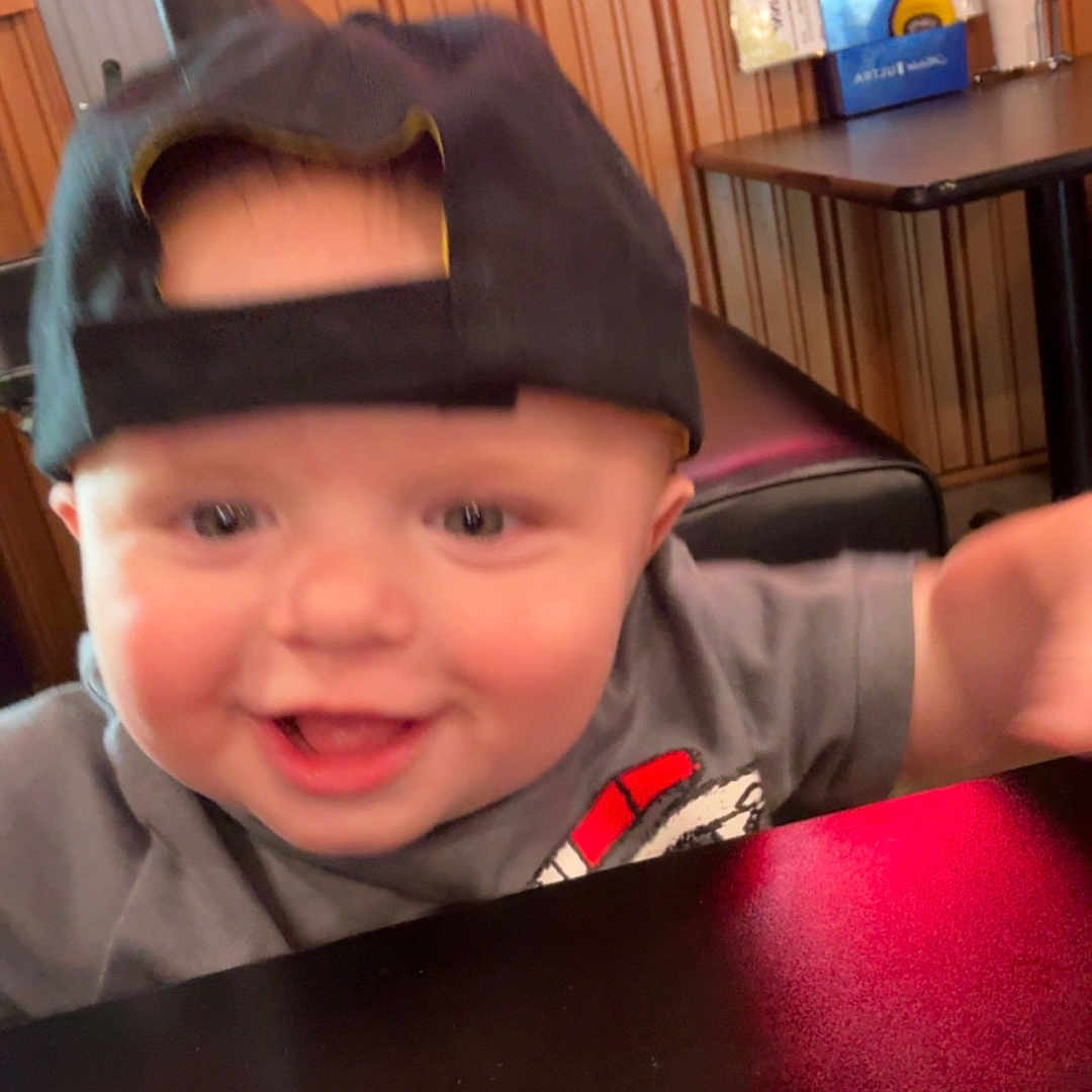 Ray joined the competition — help win amazing prizes! baby, black_cap, blur, cap, casual, child, expression, face, furniture, happy, indoor, joy, person, room, shirt, smile, table, tabletop, toddler, wood_paneling