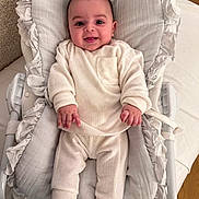 Ethan participe au concours pour gagner de l'argent avec cette photo : baby, infant, smiling, face, clothing, pillow, cushion, white, soft, bed, sleeping_bed, child, person, happy, cute, indoors, apparel, young, newborn, cozy