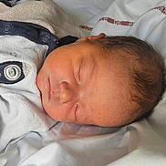 Ethan participe au concours pour gagner de l'argent avec cette photo : newborn, baby, sleeping, infant, onesie, bed, blanket, bedding, face, head, hair, closed_eyes, peaceful, tiny_hand, sleeve, fabric, cozy, portrait, soft_light, newborn_outfit