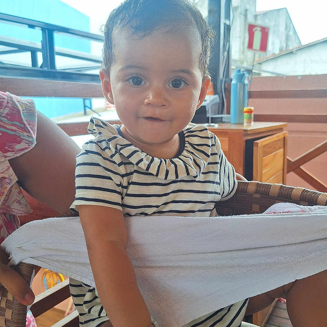 Alice a rejoint le concours — aidez-le/la à gagner de superbes lots ! baby, casual_wear, chair, child, comfortable, curious, curly_hair, cute, daylight, expression, footwear, hand, indoor, person, portrait, smiling, striped_clothing, toddler, wooden_furniture, young_child